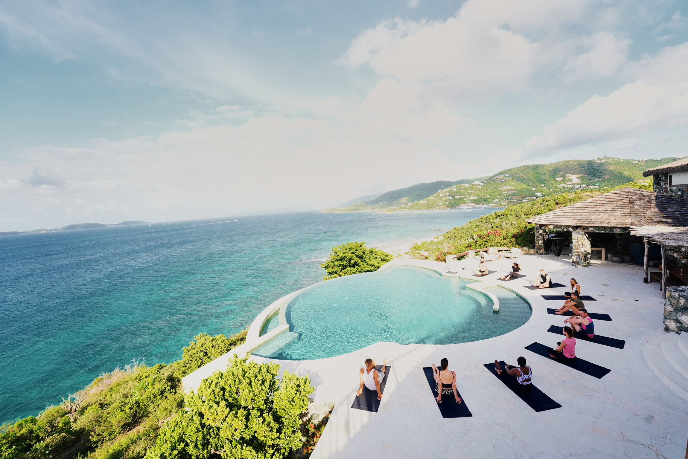 Guests doing mindful stretching by the infinity pool at The Aerial BVI